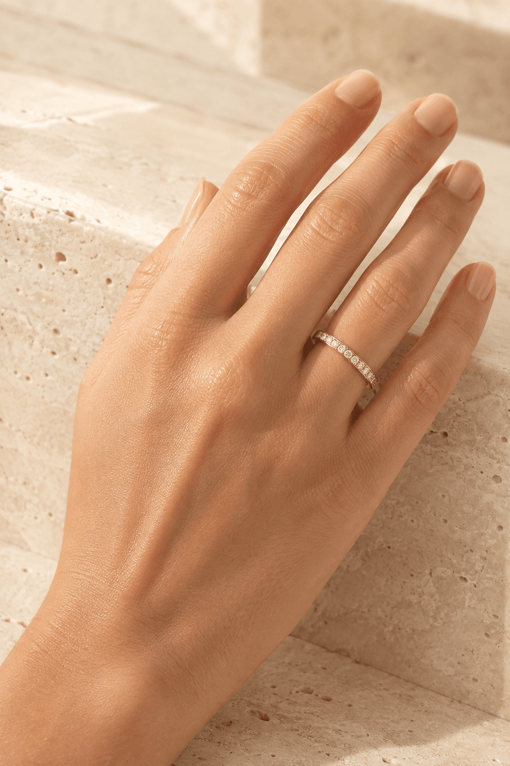 Gold diamond wedding band shown on a hand in warm light