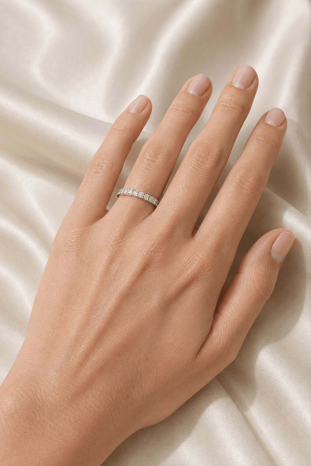 Pavé diamond wedding band worn on white silk