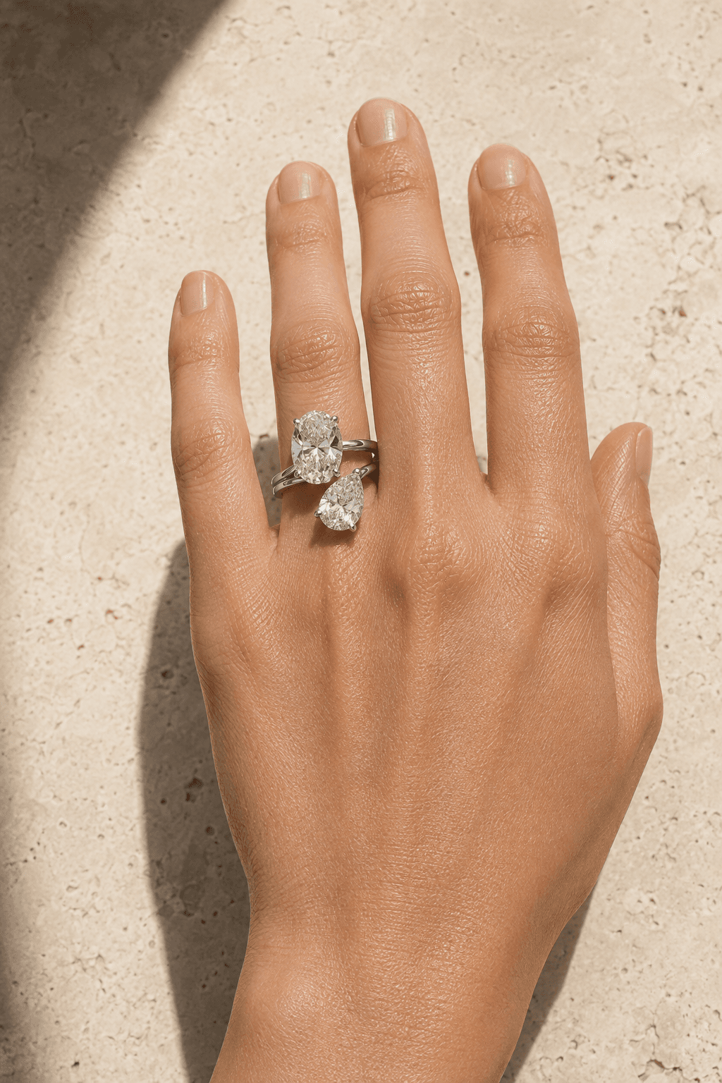 Two-stone diamond ring styled on a hand in warm natural light